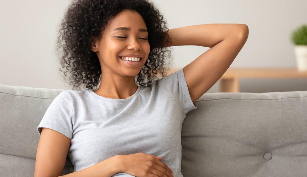 Smiling woman relaxing on a couch, illustrating the calming and euphoric effects of the Biscotti strain