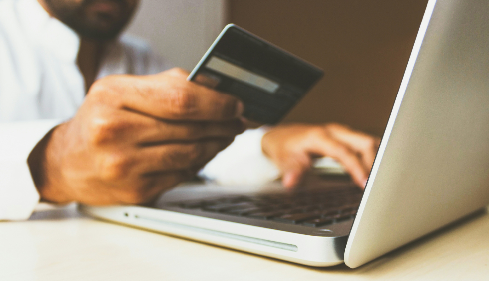 A person holding a credit card and typing on a laptop, representing buying Trainwreck weed online today