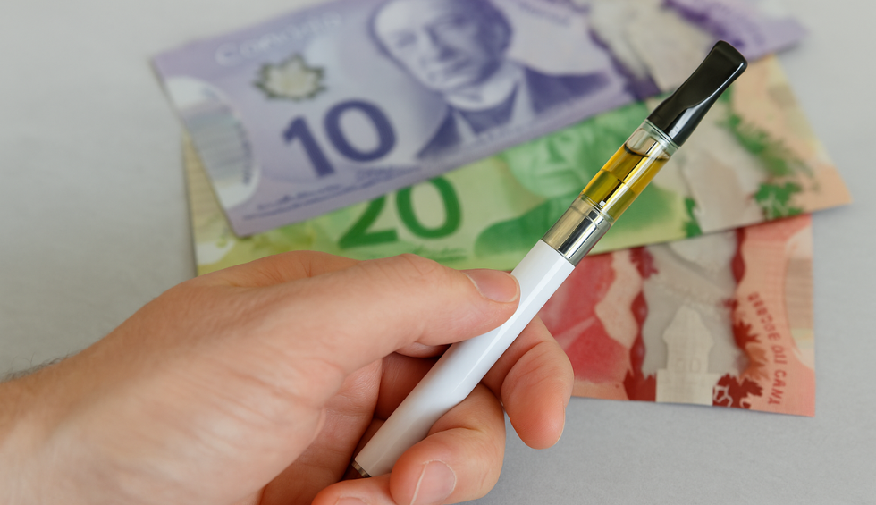 Hand holding a weed vape pen in Canada with Canadian currency in the background, symbolizing vape potency and cost