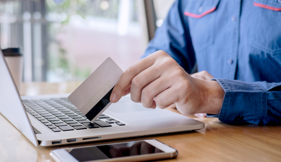 Person shopping online with a credit card and laptop, symbolizing buying top strains of weed based on desired aroma or flavour