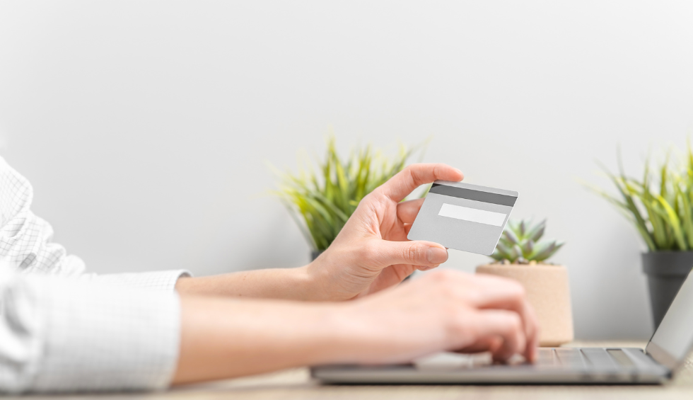 Person holding credit card and typing on laptop, representing a seamless checkout for buying online pot from BC