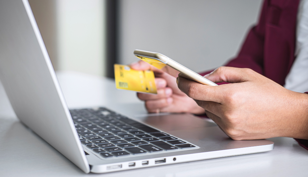 Person using credit card and smartphone to shop online on a laptop, symbolizing how to get the best deals without sacrificing quality