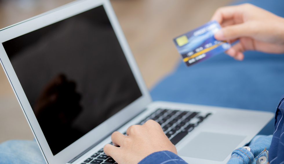 Person holding a credit card and using a laptop to purchase live resin online in Canada