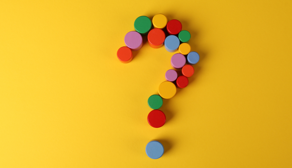 Colorful round pieces arranged in a question mark shape on a bright yellow background for cannabis edibles FAQ section